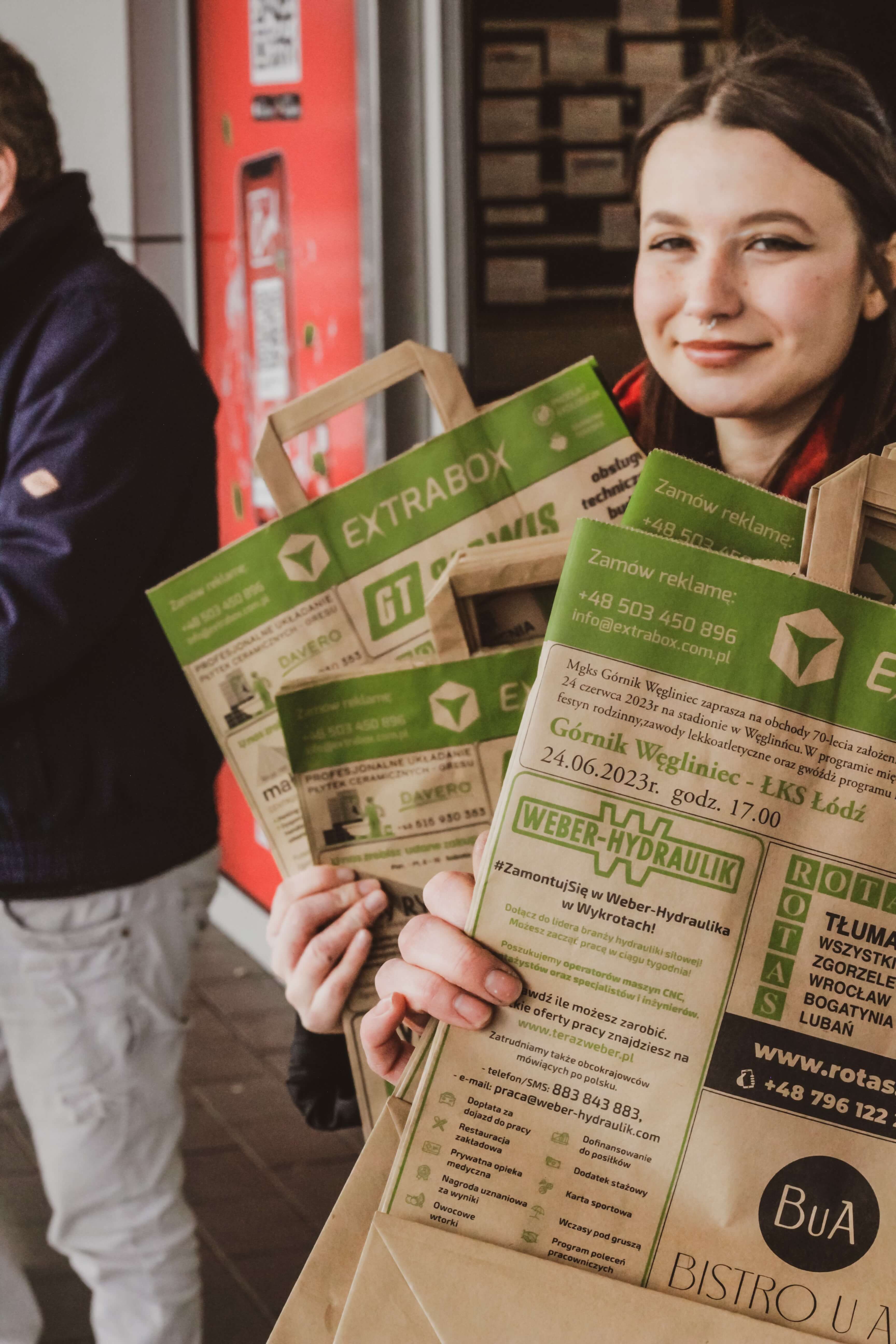 uśmiechnięta młoda dziewczyna w tle, na pierwszym planie zbliżenie torby extrabox